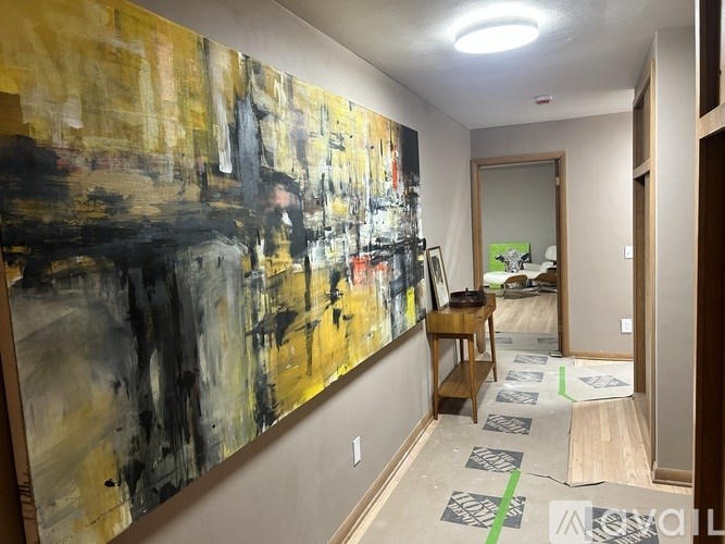 A hallway with a large painting on the wall and a door on the right.