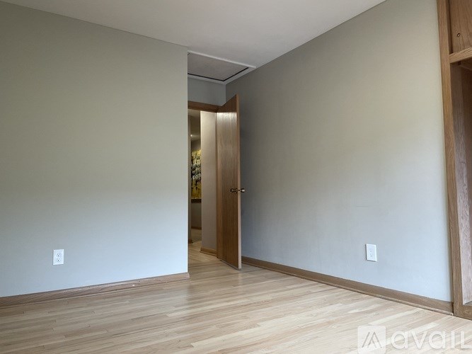 A hallway with a wooden floor and a door on the right.