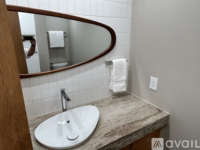 A bathroom with a marble countertop and a round mirror.