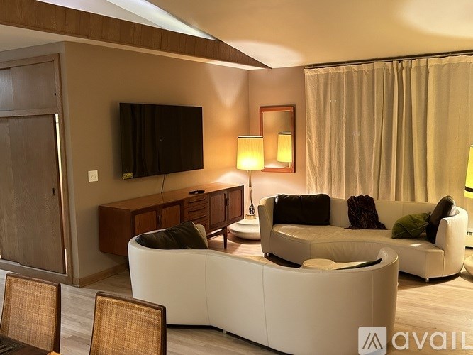 A modern living room with a white couch and a flat screen TV mounted on the wall.