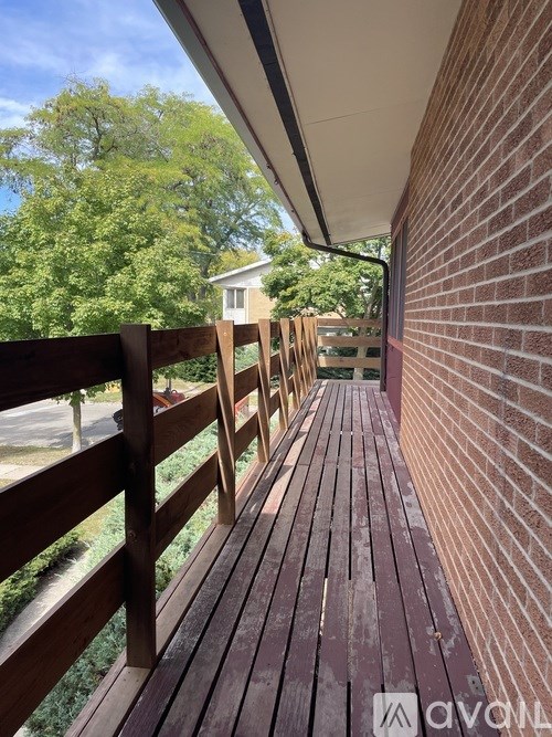 A wooden deck with a railing and a brick wall.