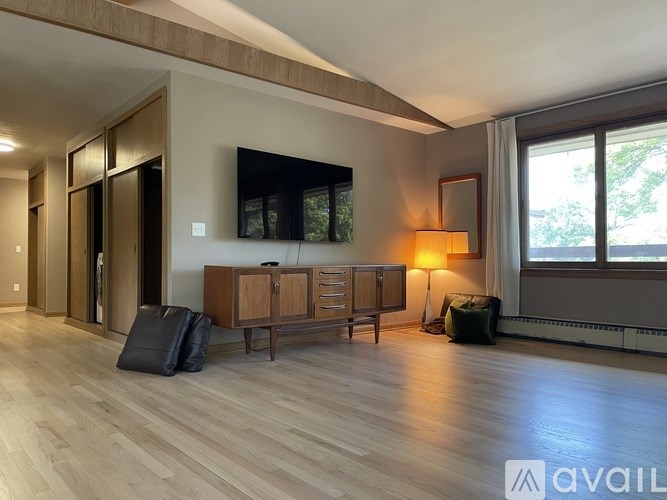 A living room with a wooden floor and a flat screen TV mounted on the wall.