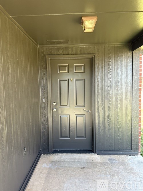 A grey door is in a room with wooden walls.