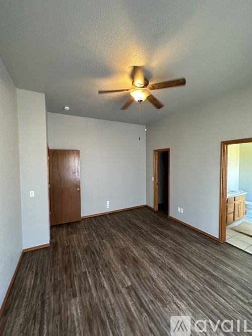 A room with a ceiling fan and wooden flooring.