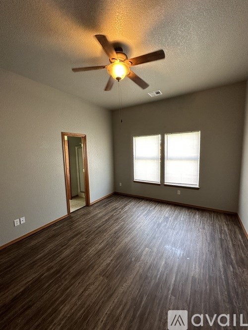 A room with a ceiling fan and wooden flooring.