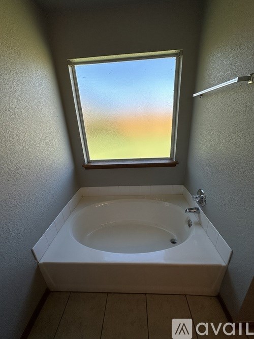 A white bathtub in a bathroom with a window.