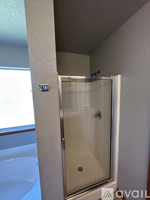 A bathroom with a glass shower door and a tub.