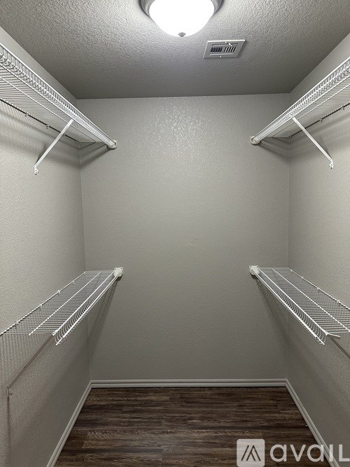 A walk-in closet with shelves and a wooden floor.
