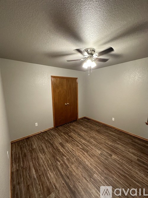 A room with a ceiling fan and wooden flooring.