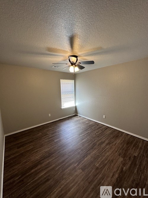 A room with a ceiling fan and wooden flooring.