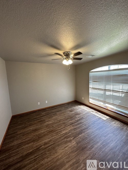 A room with a ceiling fan and wooden flooring.