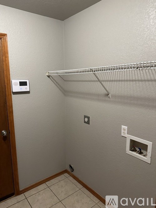 A small room with a door, a shelf, and a thermostat.