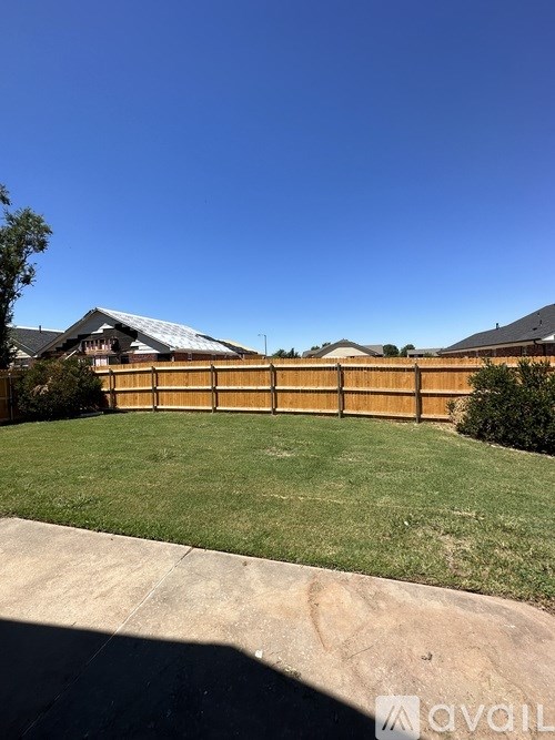 A backyard with a wooden fence and a house in the background.