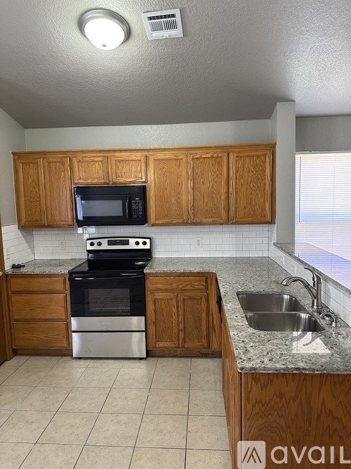 A kitchen with wooden cabinets and a black microwave above the stove.