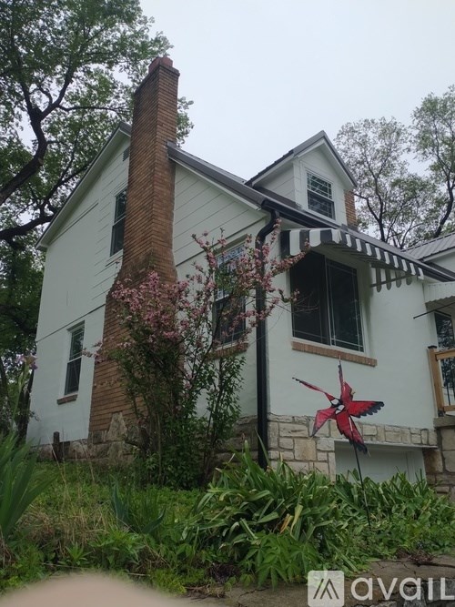 A white house with a red bird decoration in front.