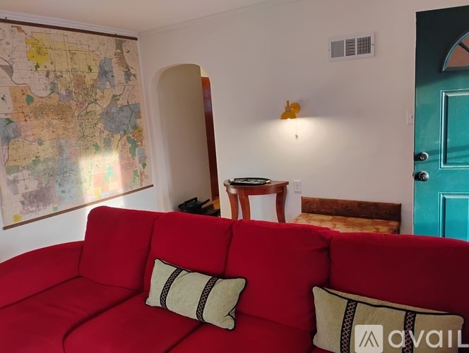 A red couch with two pillows sits in a room with a map on the wall.