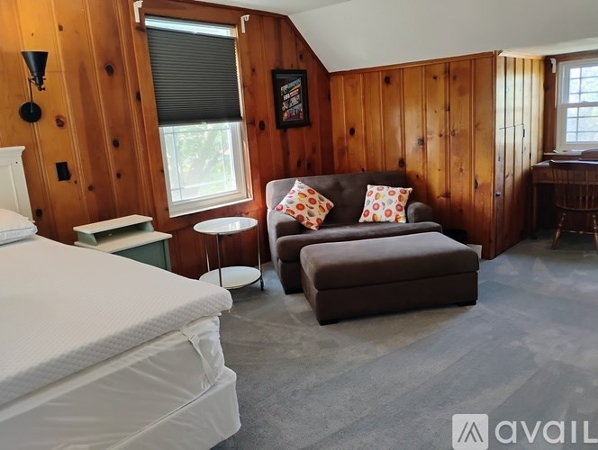 A bedroom with a bed, chair, and a window.