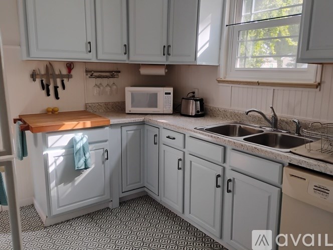 A kitchen with a wooden cutting board and a microwave on the counter.