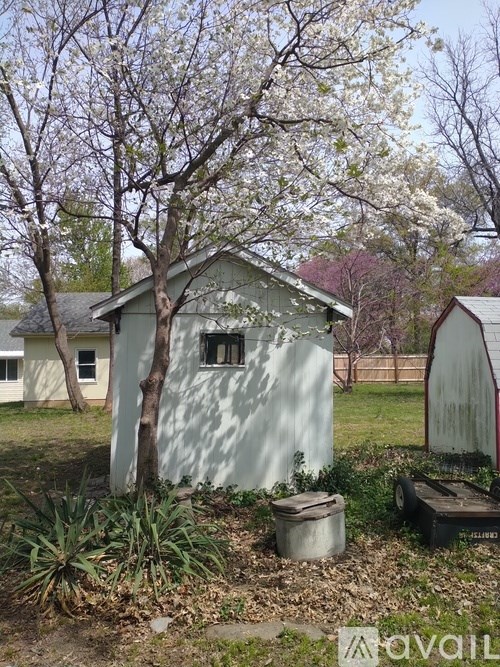 A tree with white flowers is in front of a white house.