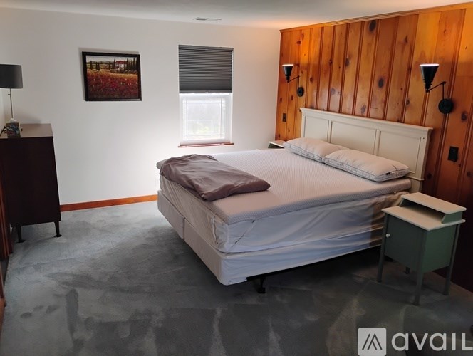 A bedroom with a large bed, wooden headboard, and a window with blinds.