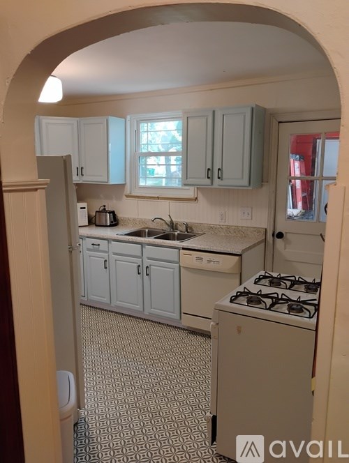 A kitchen with a white stove and a tiled floor.