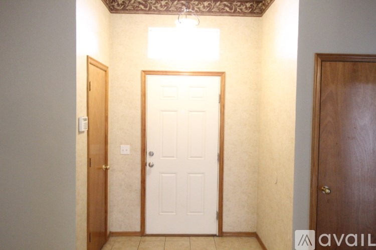 A hallway with a white door and a brown door on the right.