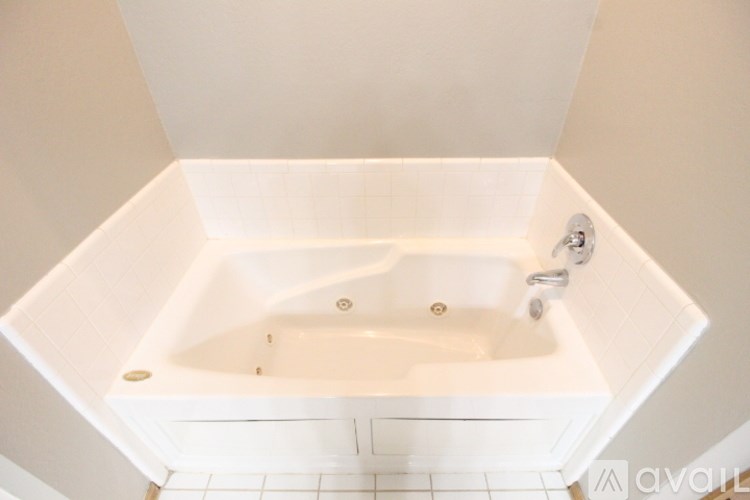 A white bathtub with a shower head and faucet.