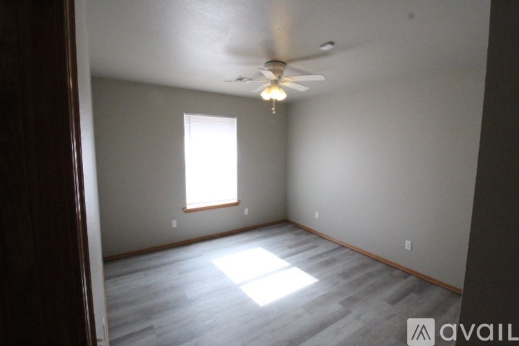A room with a ceiling fan and a window letting in sunlight.