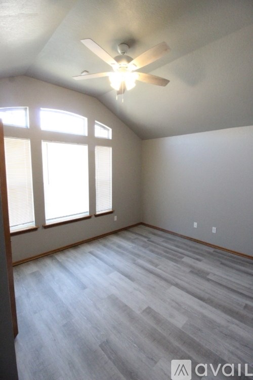 A room with a ceiling fan and wooden flooring.