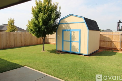 A blue and white octagonal shaped building with a black roof is situated in a grassy backyard.
