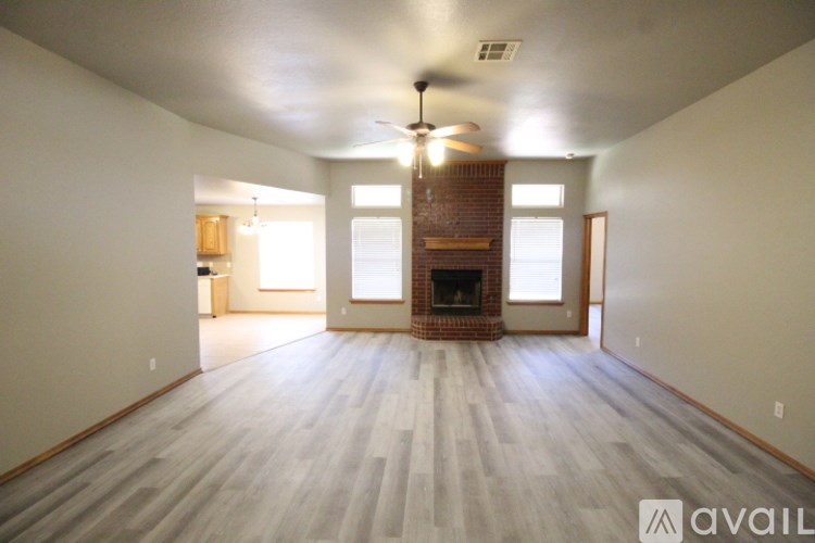 A spacious room with a fireplace and a ceiling fan.