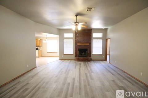 A spacious room with a fireplace and a ceiling fan.