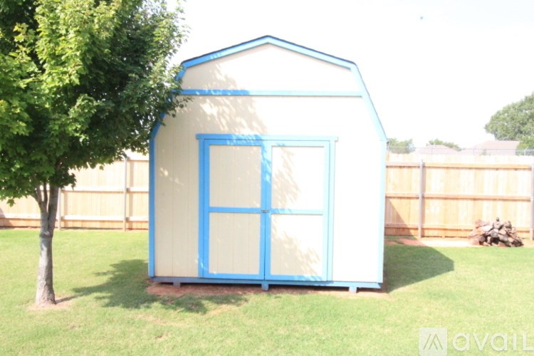 A blue and white playhouse with a tree in front of it.