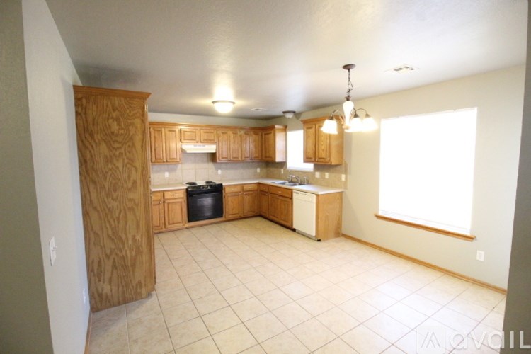 A kitchen with wooden cabinets and a black trash can.