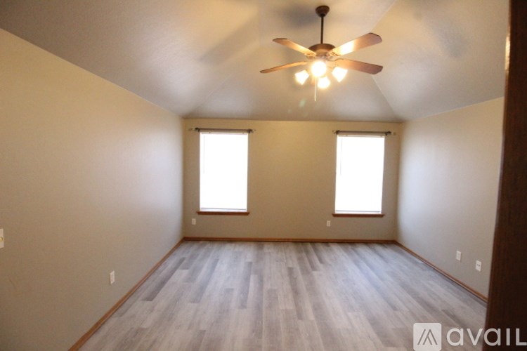 A room with a ceiling fan and two windows.