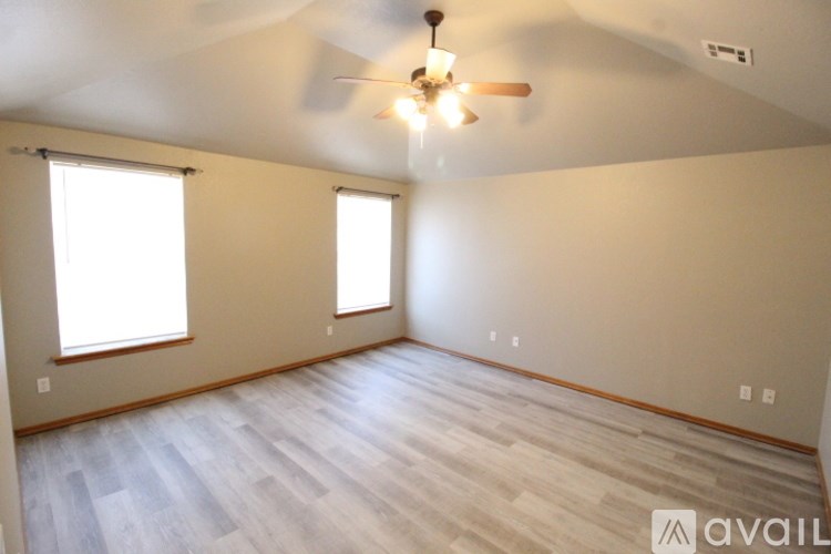 A room with a ceiling fan and wooden flooring.