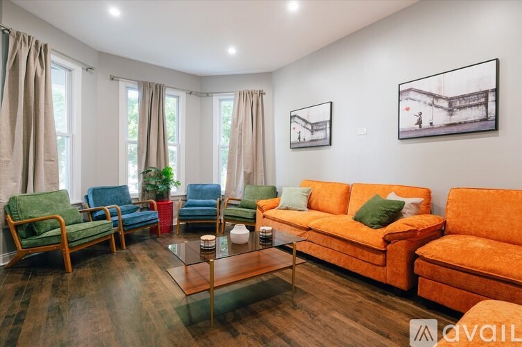 A living room with orange couch and green chairs.