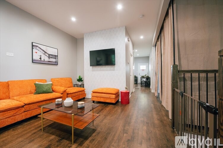 A living room with a white couch and orange cushions.