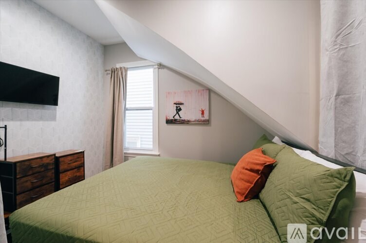 A bedroom with a green bedspread and a painting on the wall.