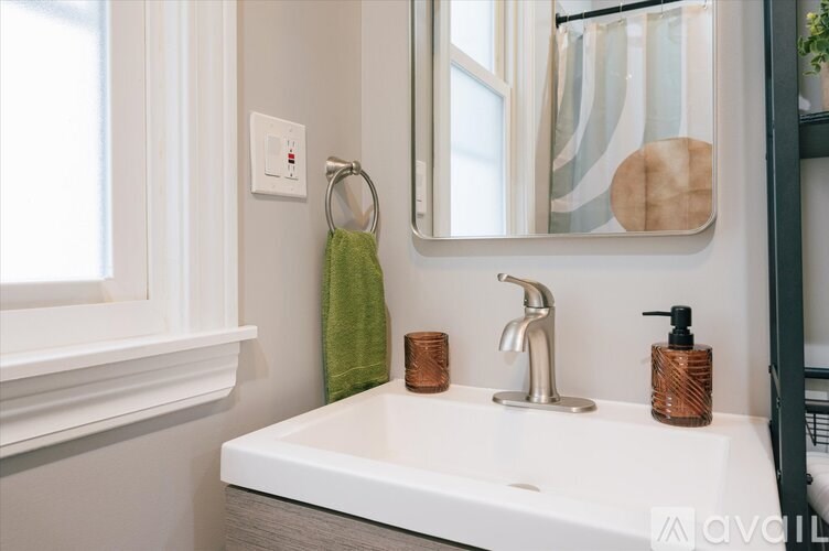 A white sink with a green towel and a mirror above it.