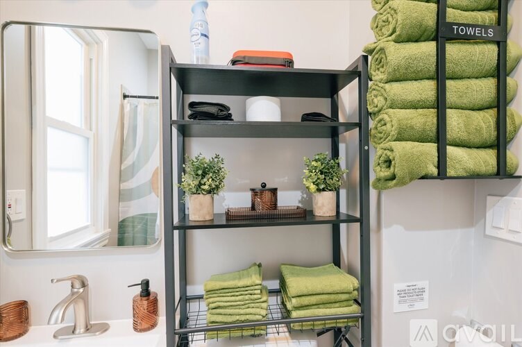 A bathroom with a towel rack and a shelf with towels and plants.