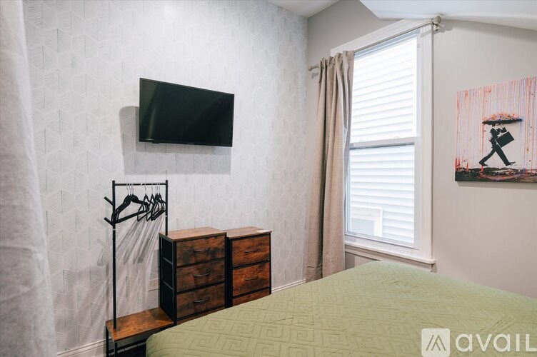 A bedroom with a bed, a dresser, and a painting on the wall.