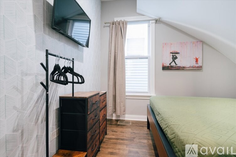 A bedroom with a bed, a dresser, and a painting on the wall.