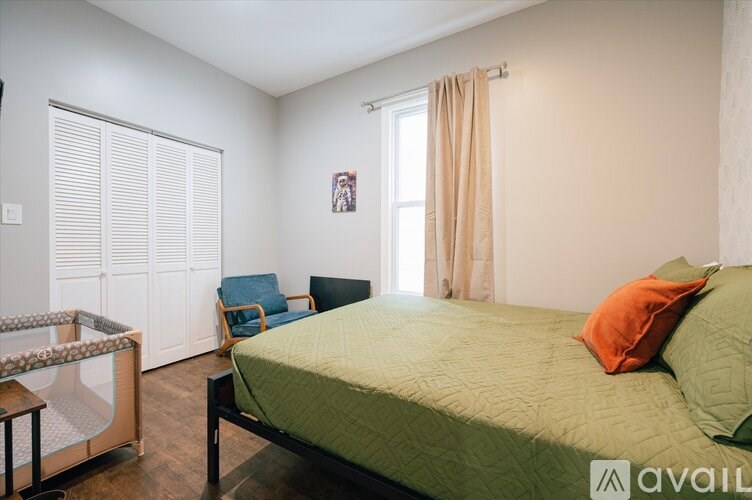 A bedroom with a bed, chair, and window.