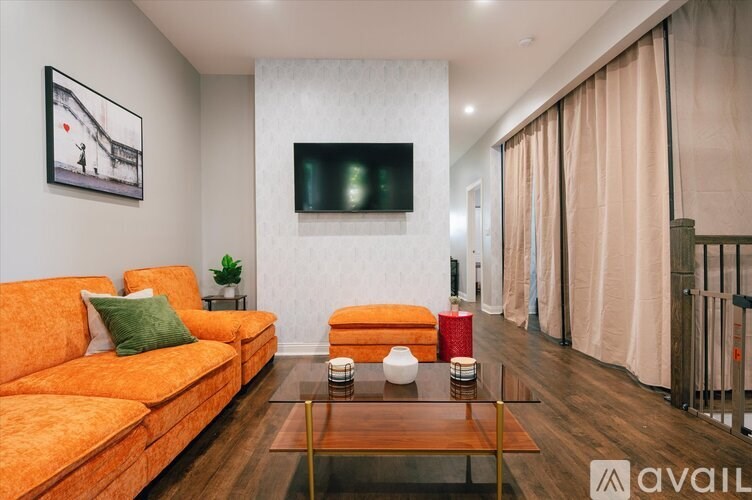 A living room with a television, orange couch, and a glass coffee table.