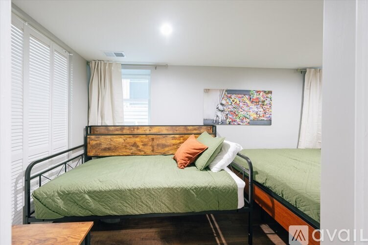 A bedroom with a bed, nightstand, and window with blinds.