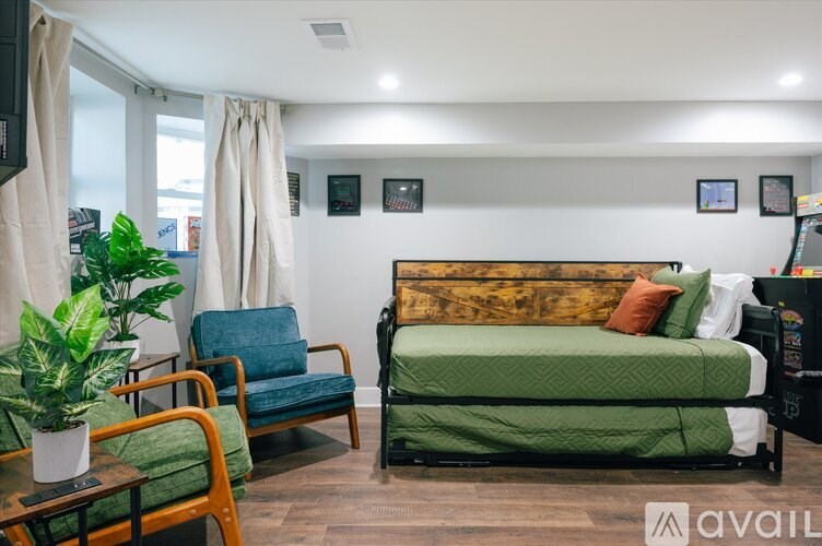 A room with a bed, chair, and potted plant.