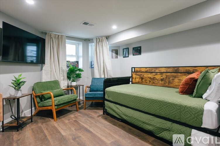 A bedroom with a green bed, a chair, and a TV.