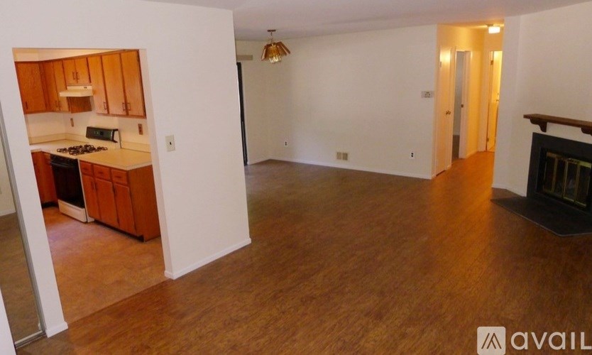 A living room with a fireplace and a hallway leading to a door.