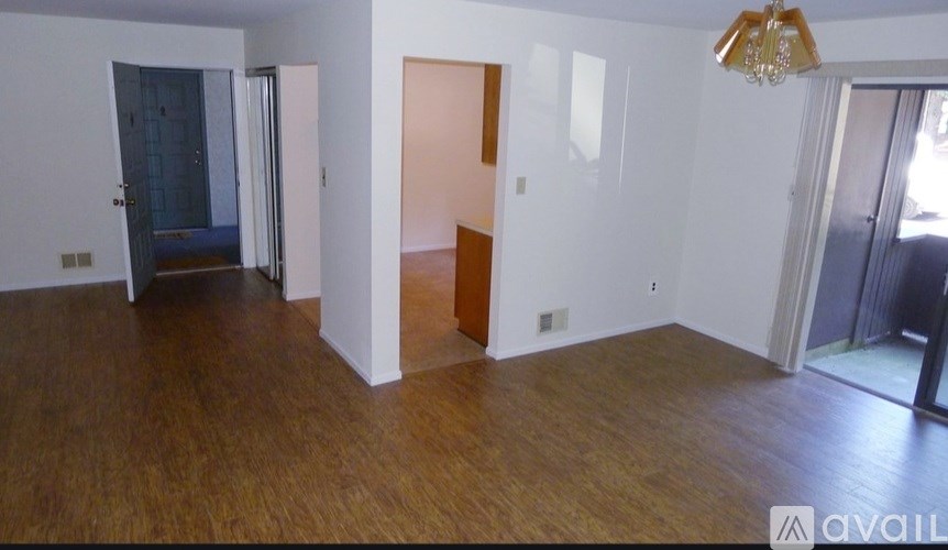 A room with wooden floors and white walls, with a chandelier hanging from the ceiling.